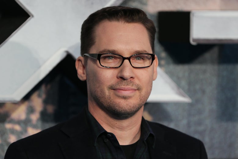 Bryan Singer poses in suit and black rimmed glasses.